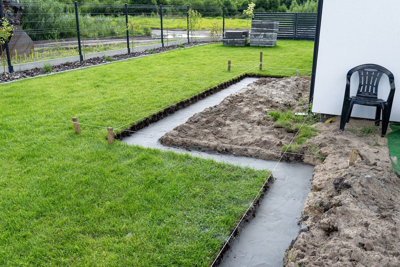 Abgestecktes Planum mit Fundamentgraben zur Vorbereitung eines Gartenwegs im professionellen Wegebau